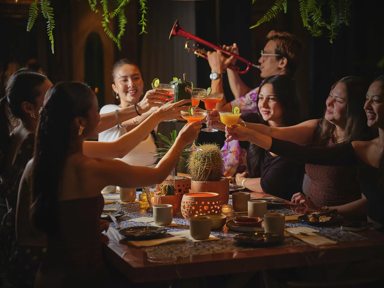 Friends raise their glasses over a table of shared plates at Madura rooftop