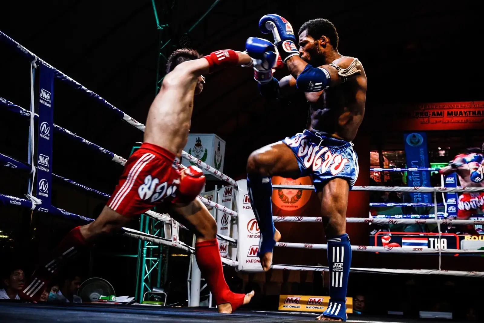 Two Muay Thai fighters trade kicks under the ring lights in Bangkok
