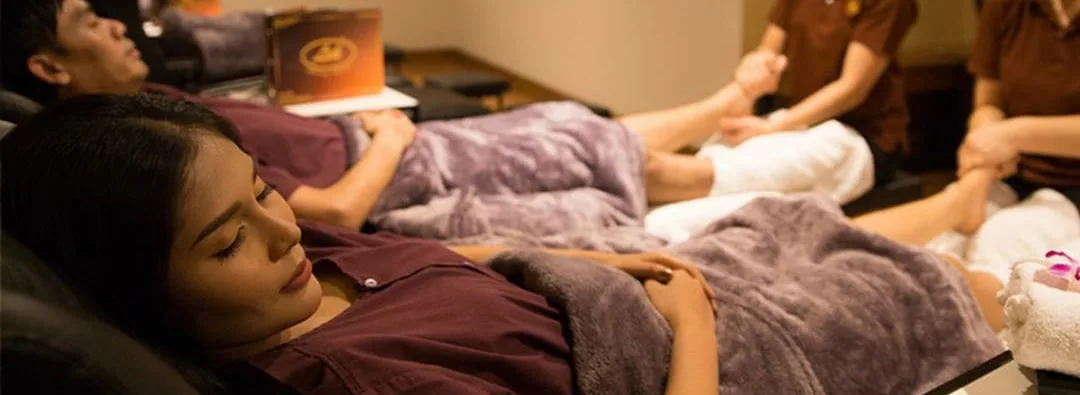 Guests relaxing in reclining chairs during a foot massage at Lek Massage