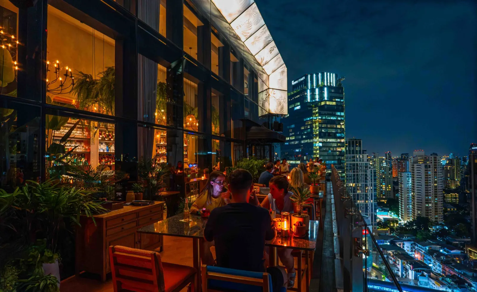 Madura rooftop terrace at night with the Bangkok skyline