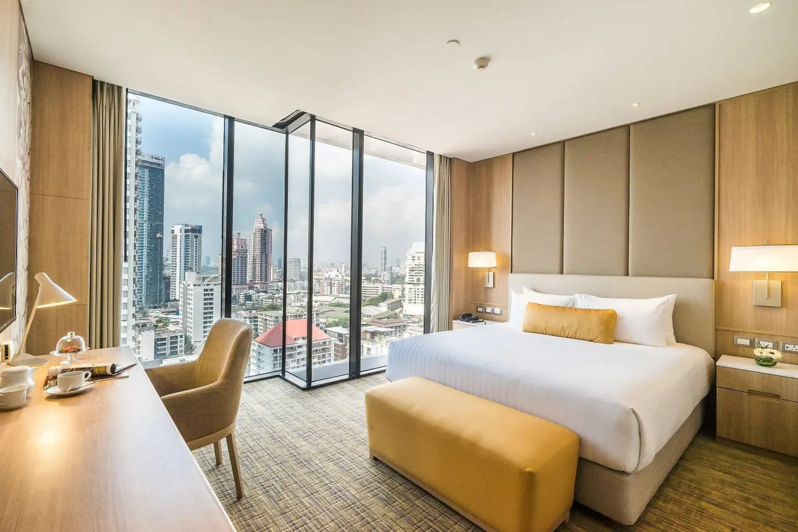 Hotel room with a king bed and floor-to-ceiling windows over the city