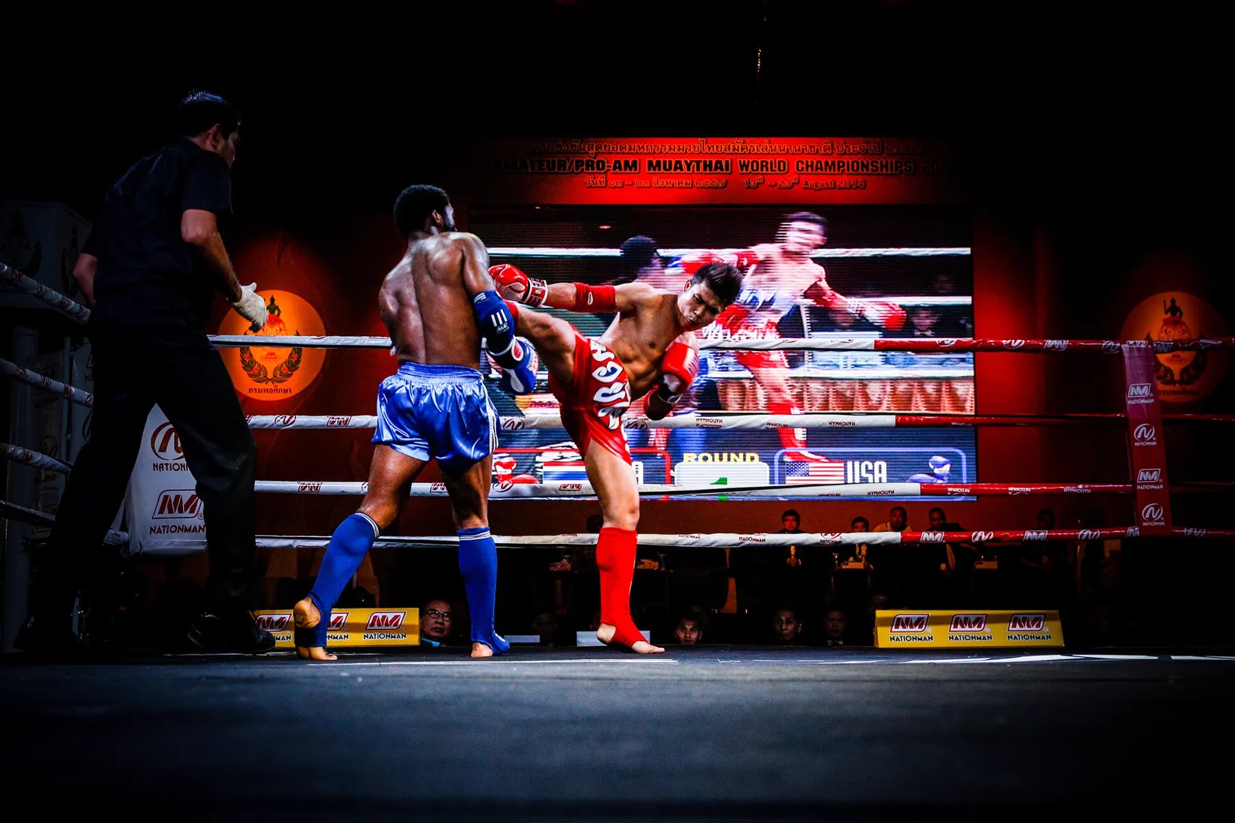 A Muay Thai fight under red stadium lights