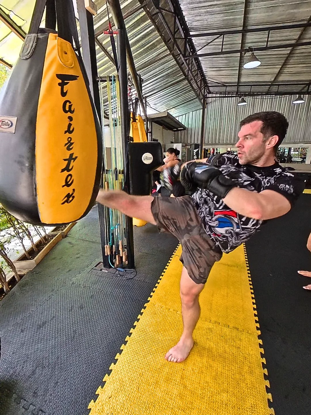 Russell throws a roundhouse kick into a Fairtex bag at a Muay Thai gym in Thailand